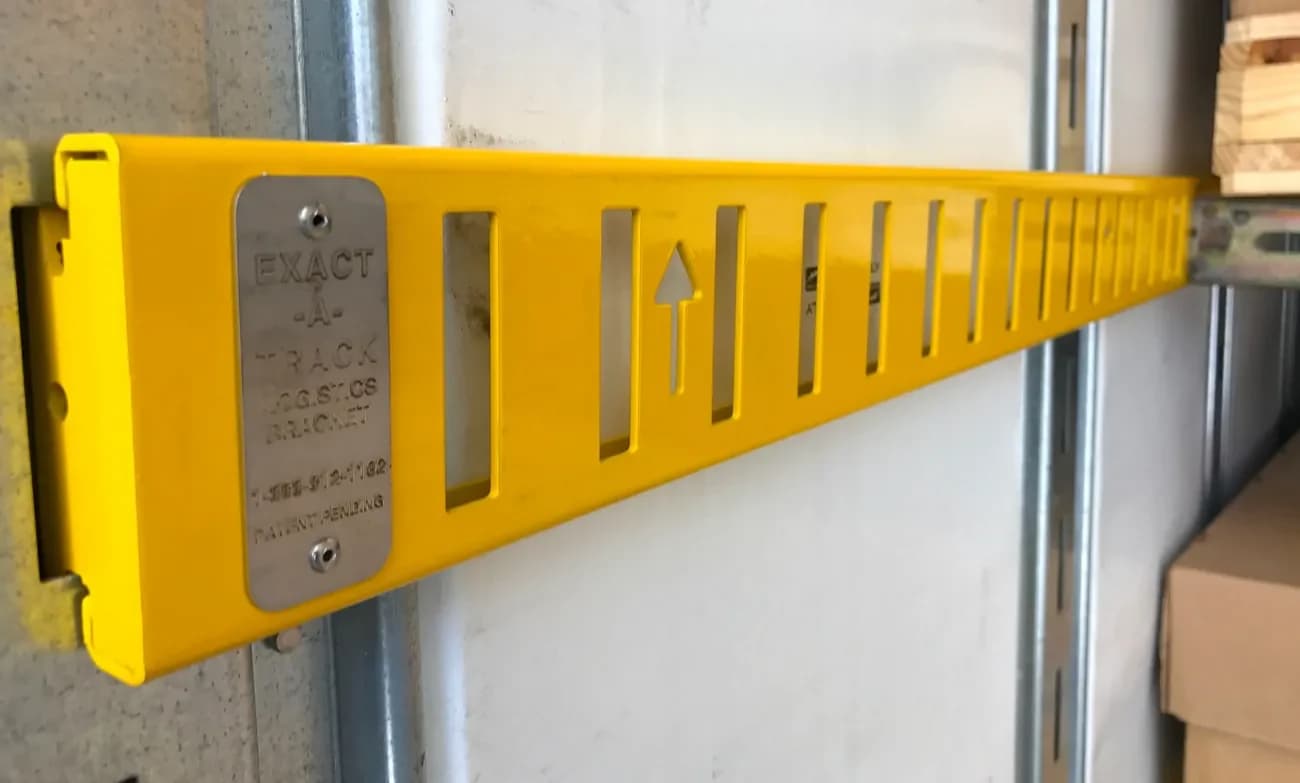 Exact-A-Track freight-stabilization product mounted into compatible vertical E-track beside palletized freight